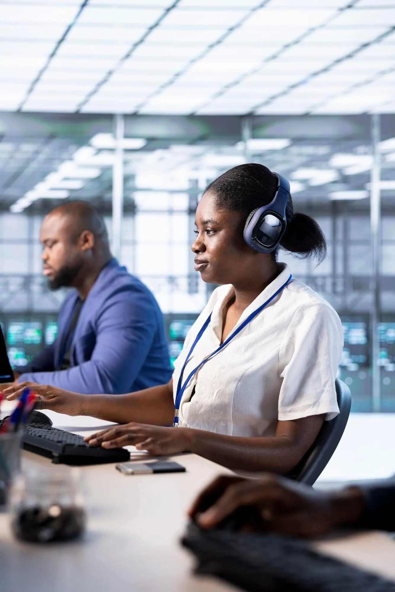 Женщина в дата-центре в наушниках слушает музыку.