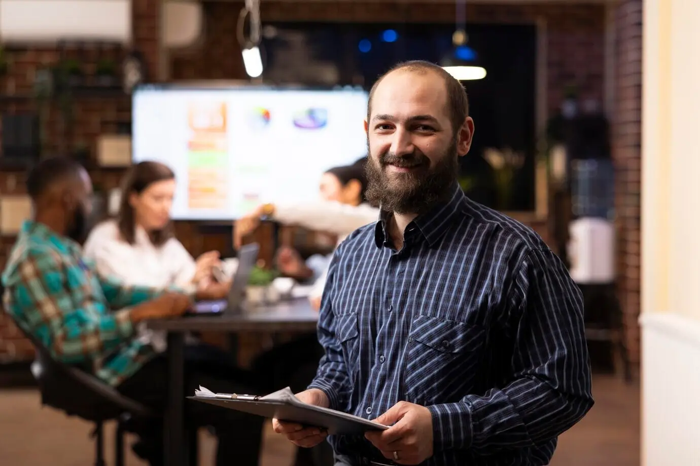 Улыбающийся в камеру бизнесмен с планшетом для бумаг.